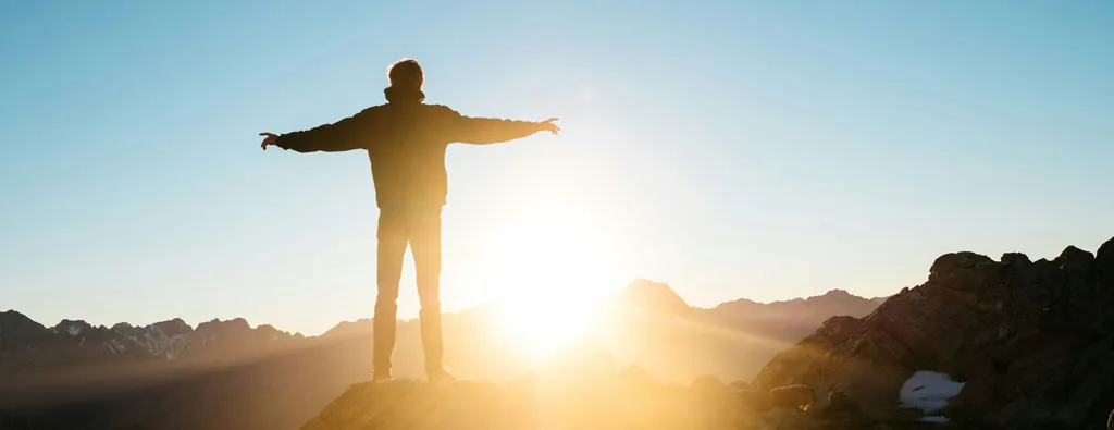 Understanding addiction. Man being free from what held him down standing on mountain