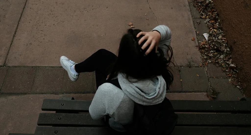 Trauma and Addiction: A lady sitting on a bench in distress 