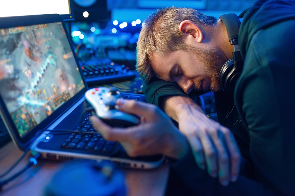 A man that is sleeping on his computer due to his gaming addiction